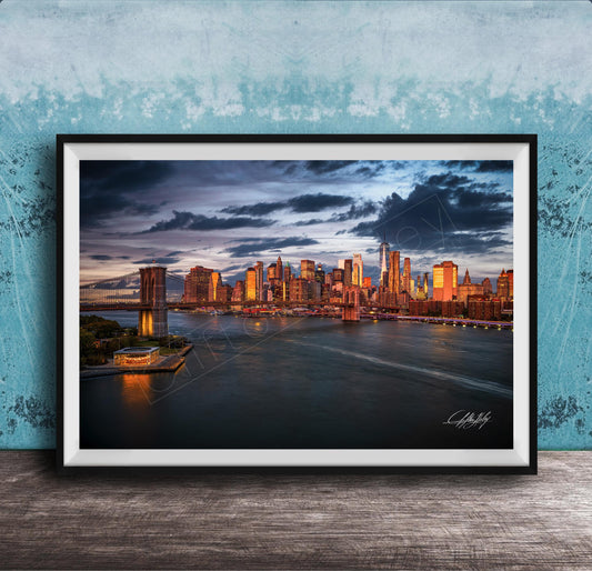 A framed photograph of the New York City skyline at dusk, with the city's iconic landmarks and buildings illuminated against a dramatic cloudy sky.