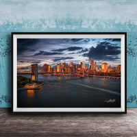 A framed photograph of the New York City skyline at dusk, with the city's iconic landmarks and buildings illuminated against a dramatic cloudy sky.