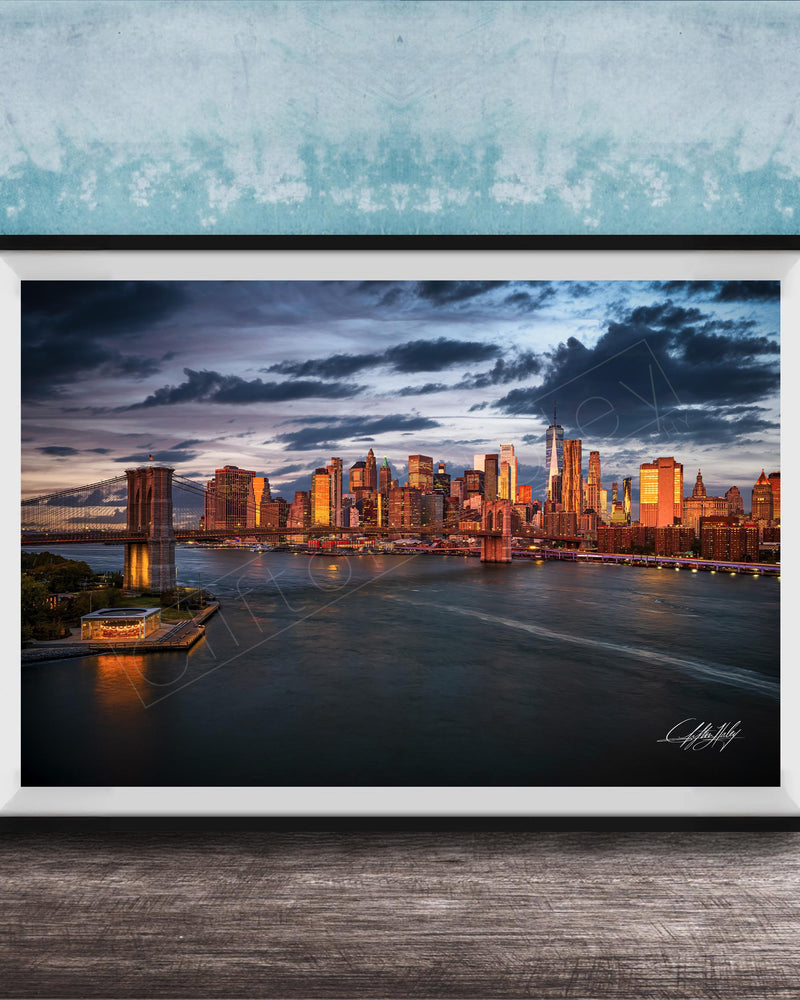 A framed photograph of the New York City skyline at dusk, with the city's iconic landmarks and buildings illuminated against a dramatic cloudy sky.