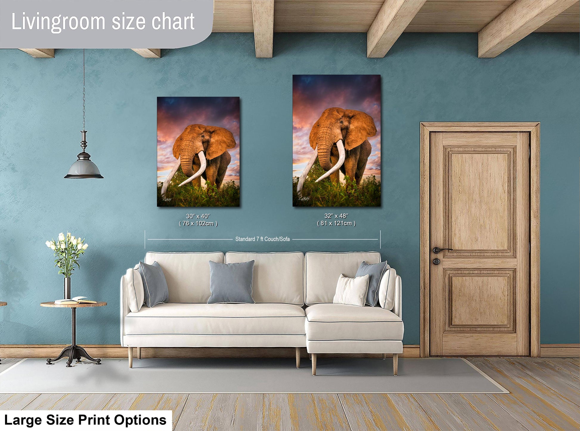 a living room with a white sofa and a wooden door. Above the sofa, there are two framed pictures of elephants, one larger than the other. The larger picture is hung at a height of approximately 75 inches, while the smaller one is at approximately 60 inches. The living room has a blue wall, and there is a lamp hanging from the ceiling.