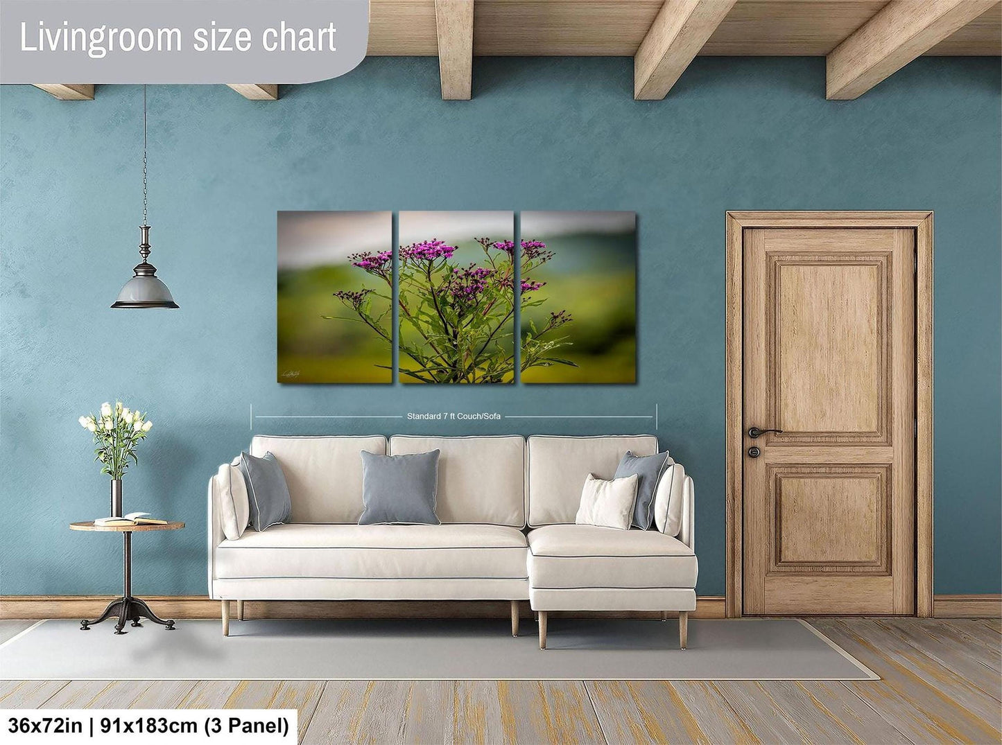 The image is a living room with a large white sofa, a wooden door, and a painting of a field of flowers hanging on the wall.