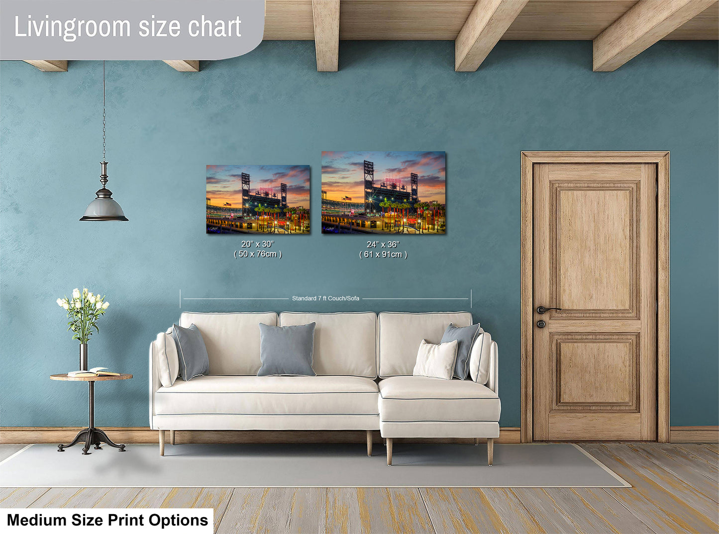a living room with a white sofa and a wooden door. Above the sofa, there are two framed pictures of a city skyline at night, with the sizes of the pictures being 24" x 36" and 28" x 36" respectively. The living room has a blue wall and a wooden floor.