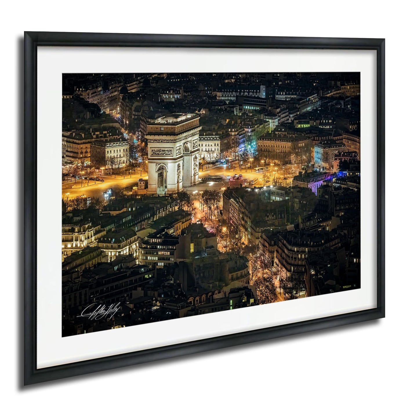 The image is a framed photograph of a city at night, featuring a large, illuminated archway or monument in the center of the frame. The surrounding buildings and streets are brightly lit, creating a vibrant and lively atmosphere.
