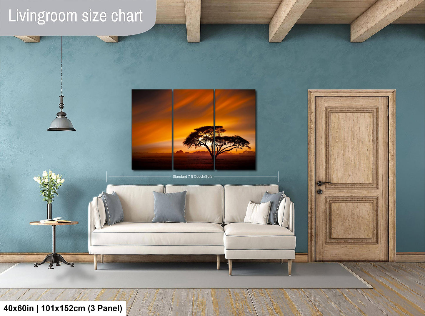 The image is a living room with a white sofa, a wooden door, and a large wall art depicting a sunset over a tree.