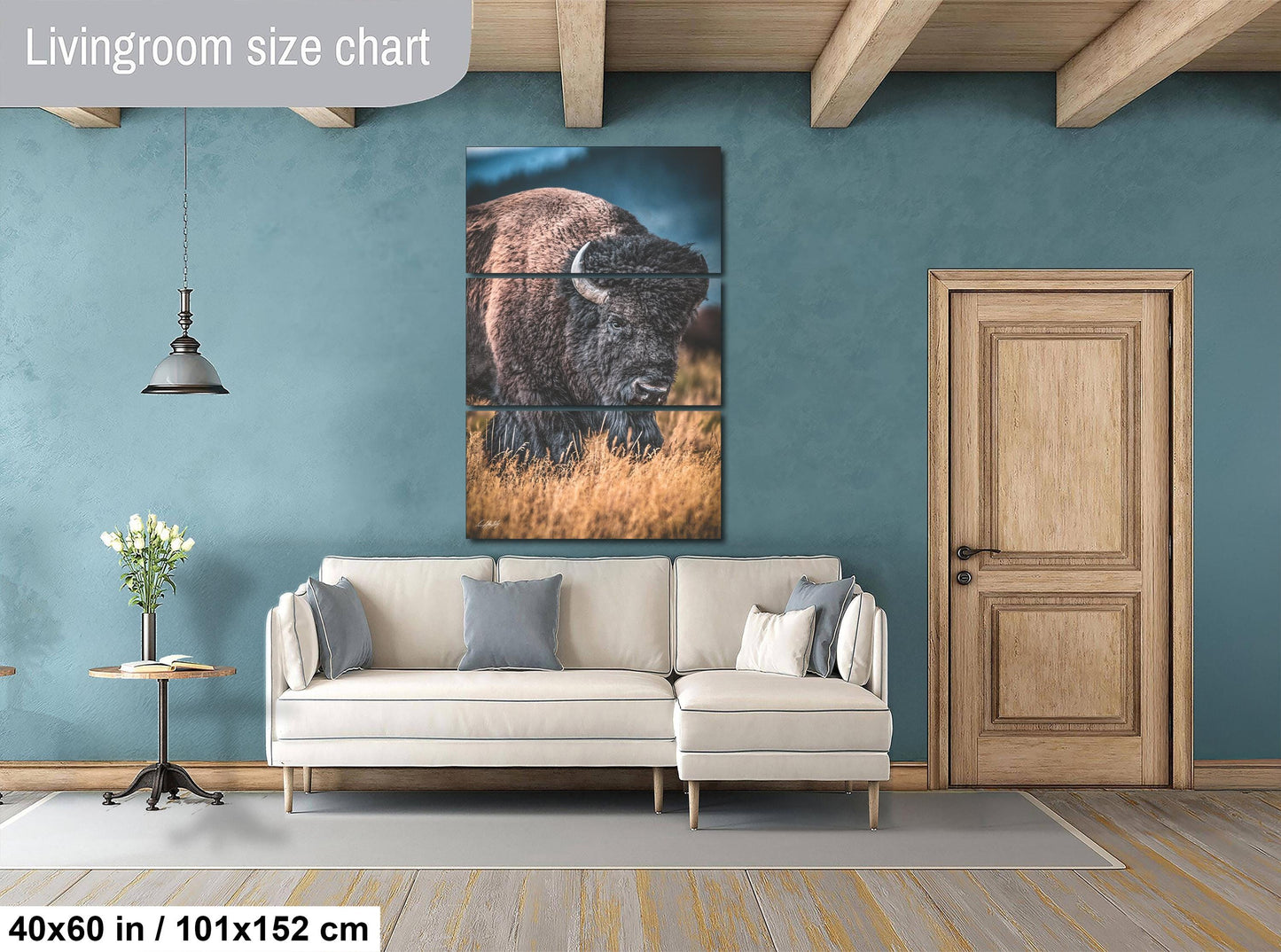 The image is a living room with a large painting of a bison on the wall, a white sofa, a wooden door, and a small table with a vase of flowers.