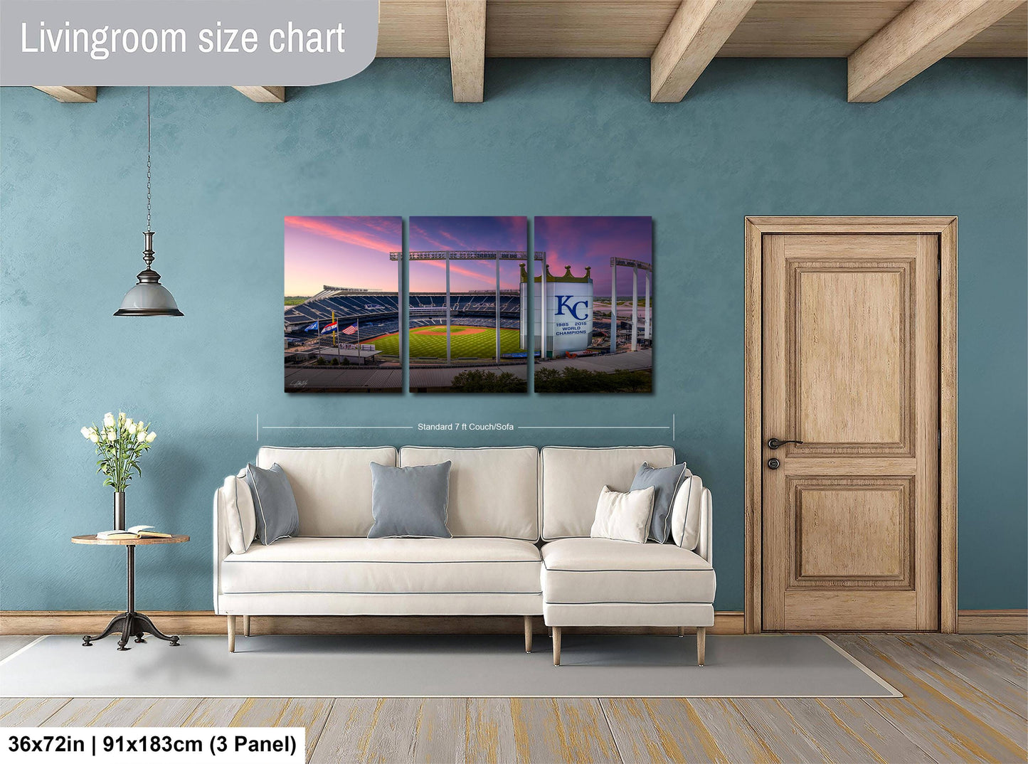 The image is a living room with a large wall-mounted painting depicting a baseball stadium. The painting is divided into three panels, with the top and bottom panels showing the stadium and the middle panel showing the field. The wall is painted in a light blue color, and there is a wooden door and a white sofa in the room.