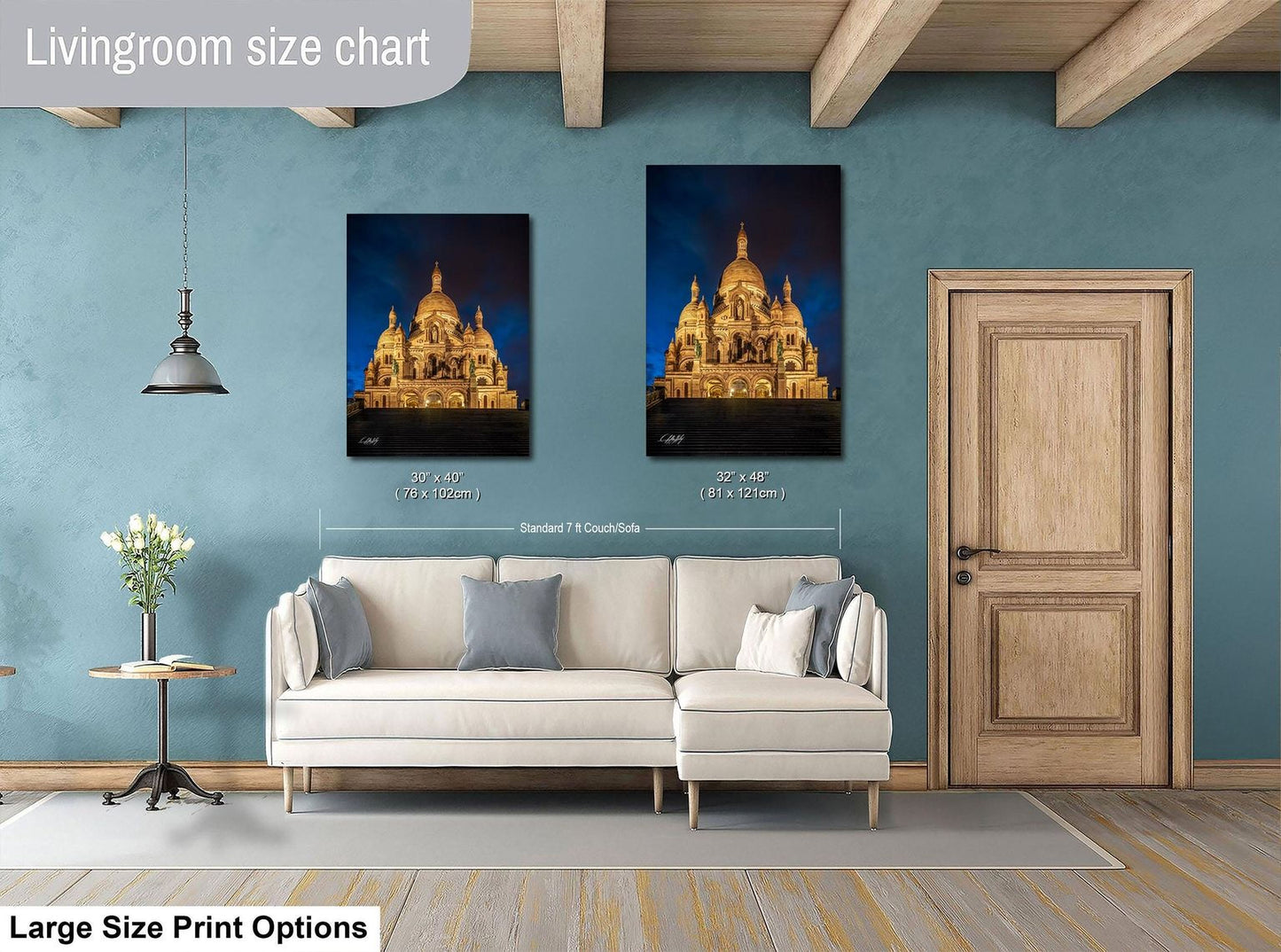 a living room with a white sofa, a wooden door, and two framed pictures of a cathedral or castle-like structure on the wall.
