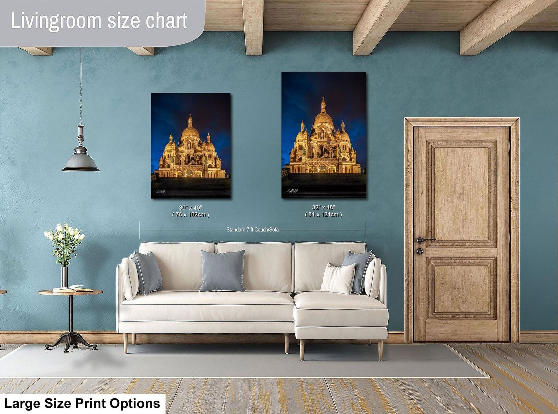 a living room with a white sofa, a wooden door, and two framed pictures of a cathedral or castle-like structure on the wall.