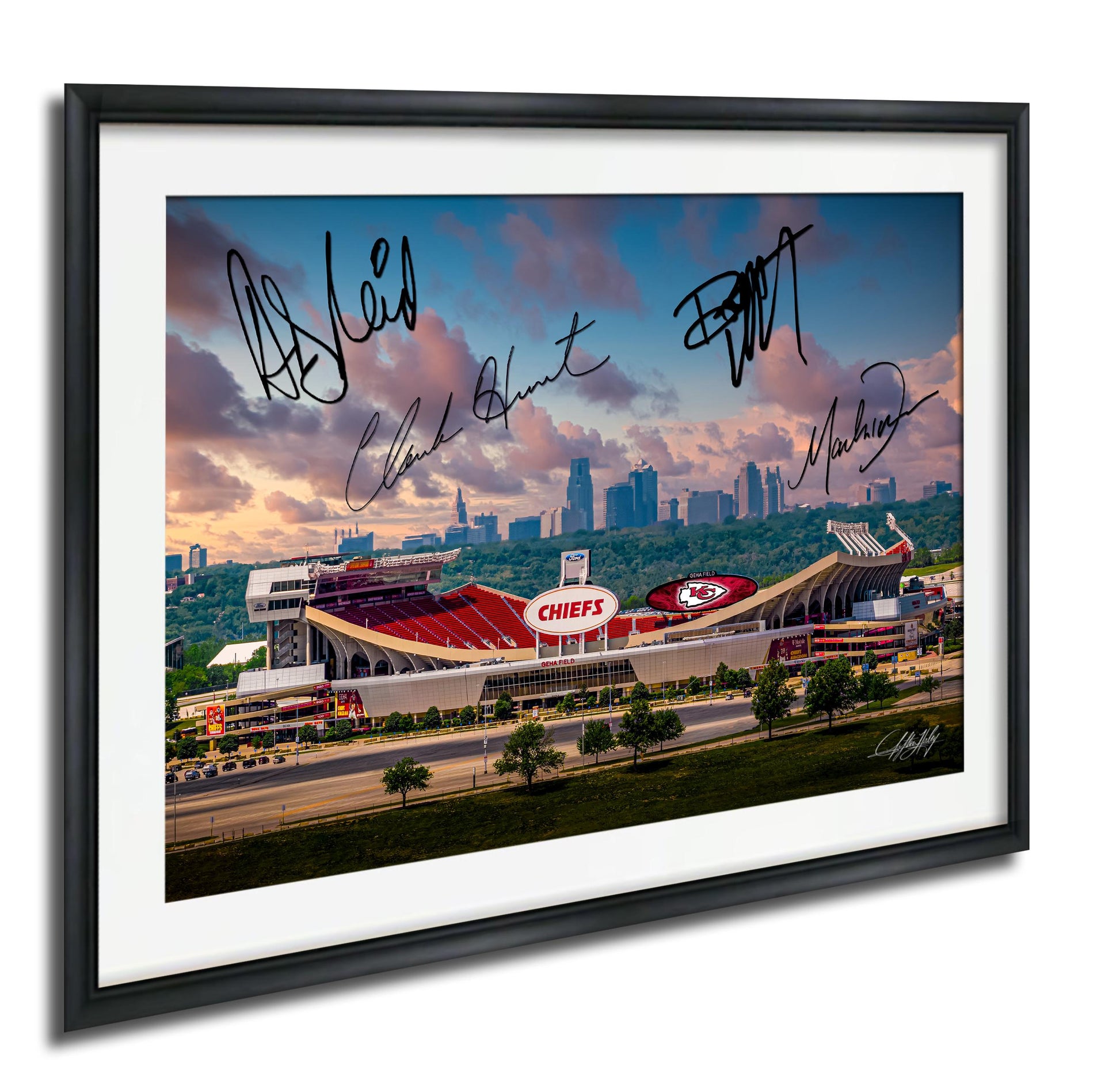 The image is a framed photograph of a football stadium with the Kansas City Chiefs logo, set against a backdrop of a city skyline and a cloudy sky.