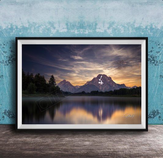 The image is a framed photograph of a serene mountain landscape at sunset, with a calm lake reflecting the vibrant colors of the sky.