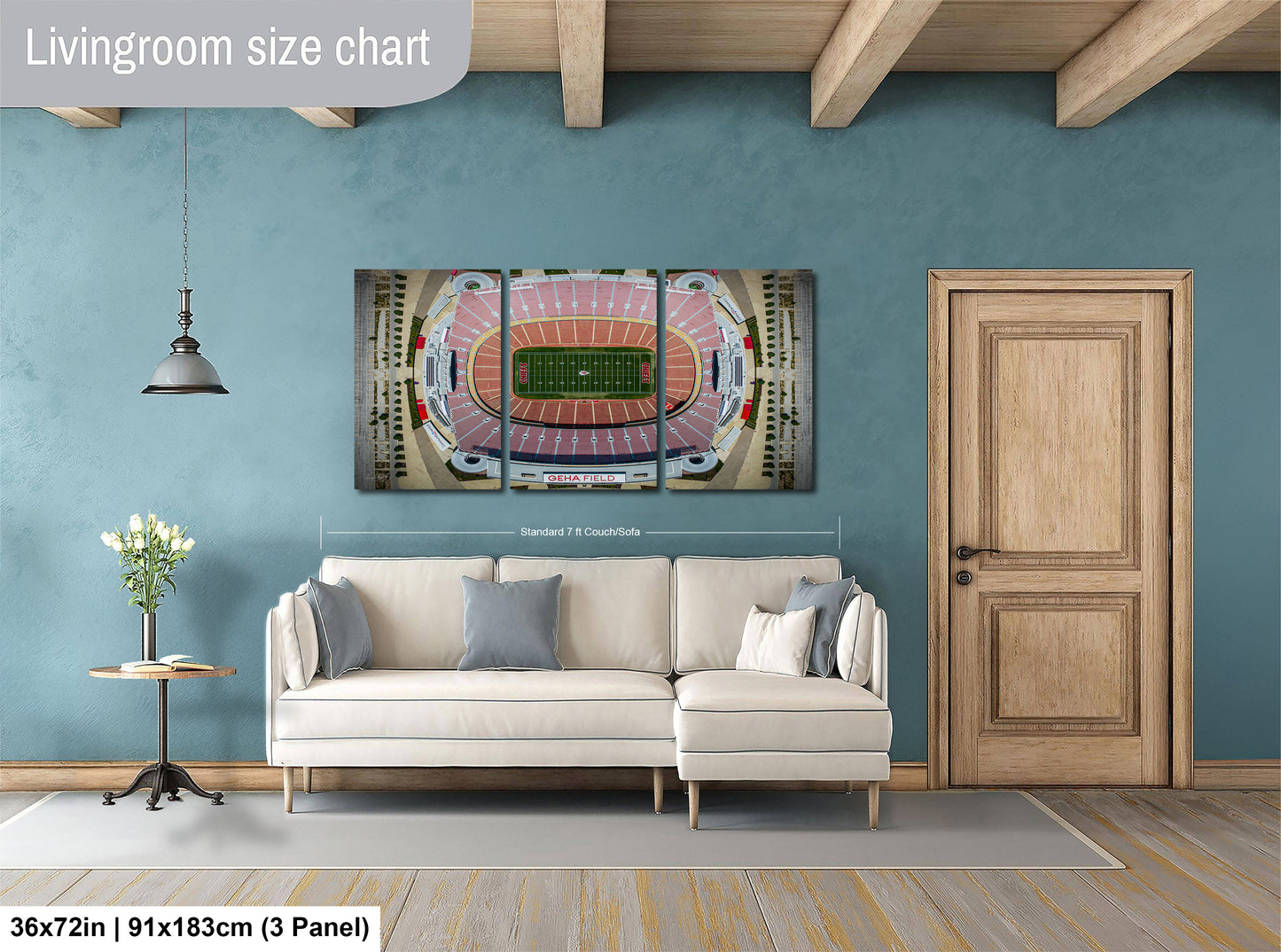 a living room with a large wall-mounted poster of a football stadium, a white sofa, a wooden door, and a small table with a vase of flowers.