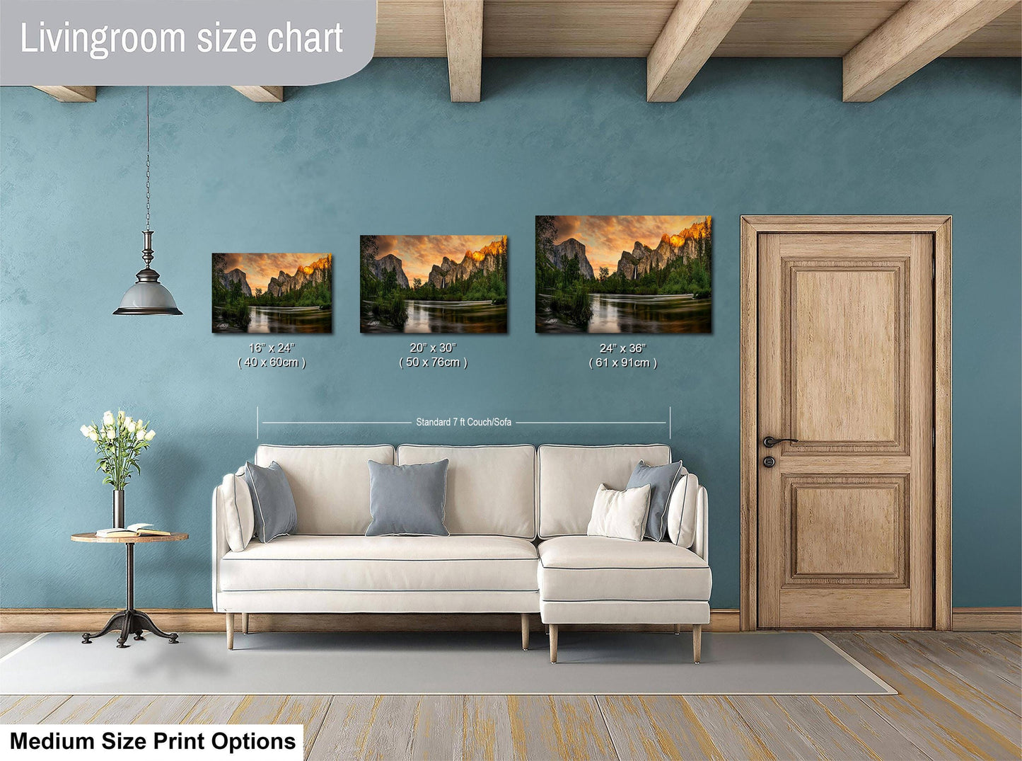 The image is a livingroom size chart with three framed landscape paintings of varying sizes, each depicting a different mountain range. The paintings are hung above a white couch, and there is a wooden door and a small table with a vase of flowers in the room.