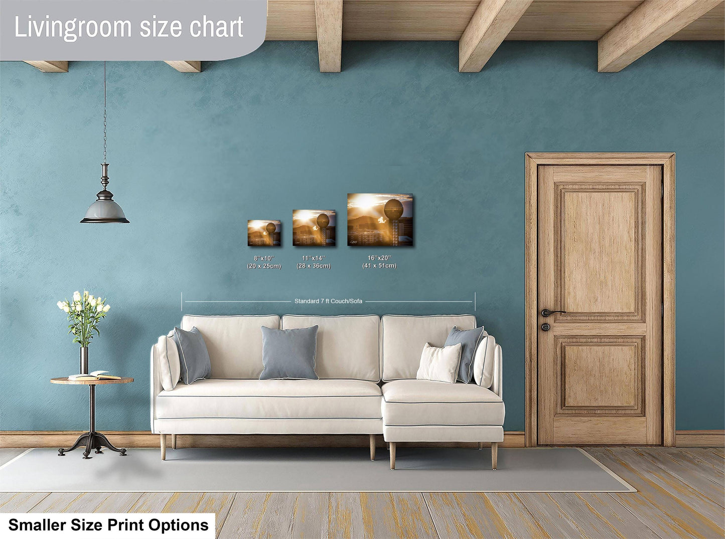 a living room with a white sofa, a wooden door, and a potted plant. There are three framed artworks hanging on the wall, each with different sizes and dimensions. The living room appears to be well-decorated and spacious.