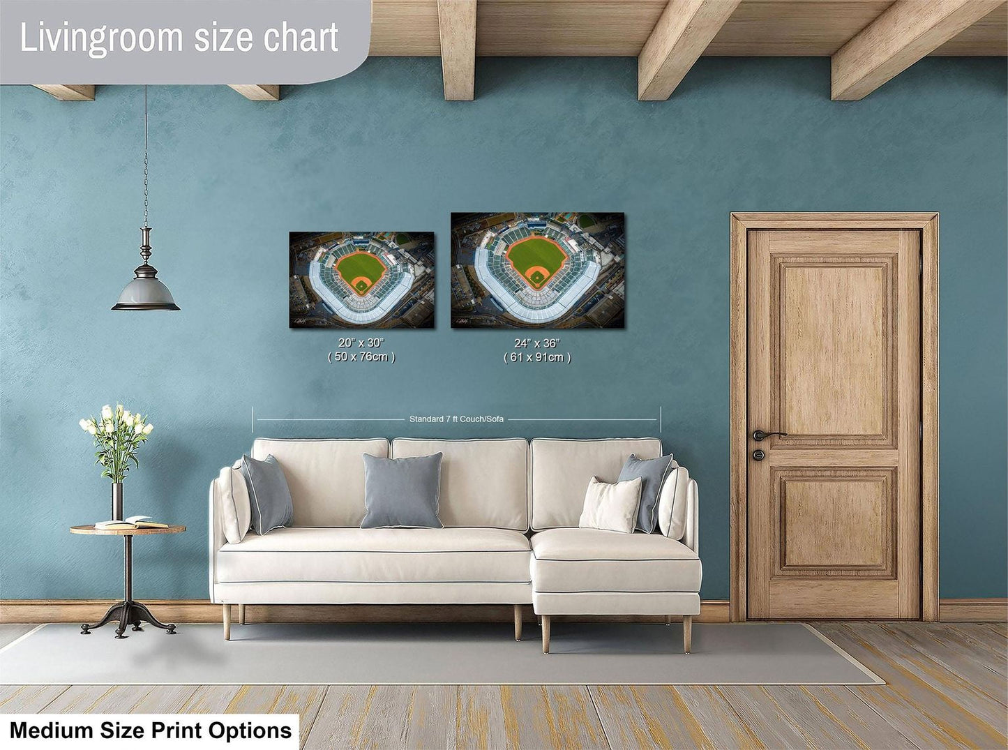 a living room with a white sofa, a wooden door, and a ceiling with wooden beams. There are two framed pictures hanging on the wall, depicting baseball fields. The living room appears to be well-lit and decorated.