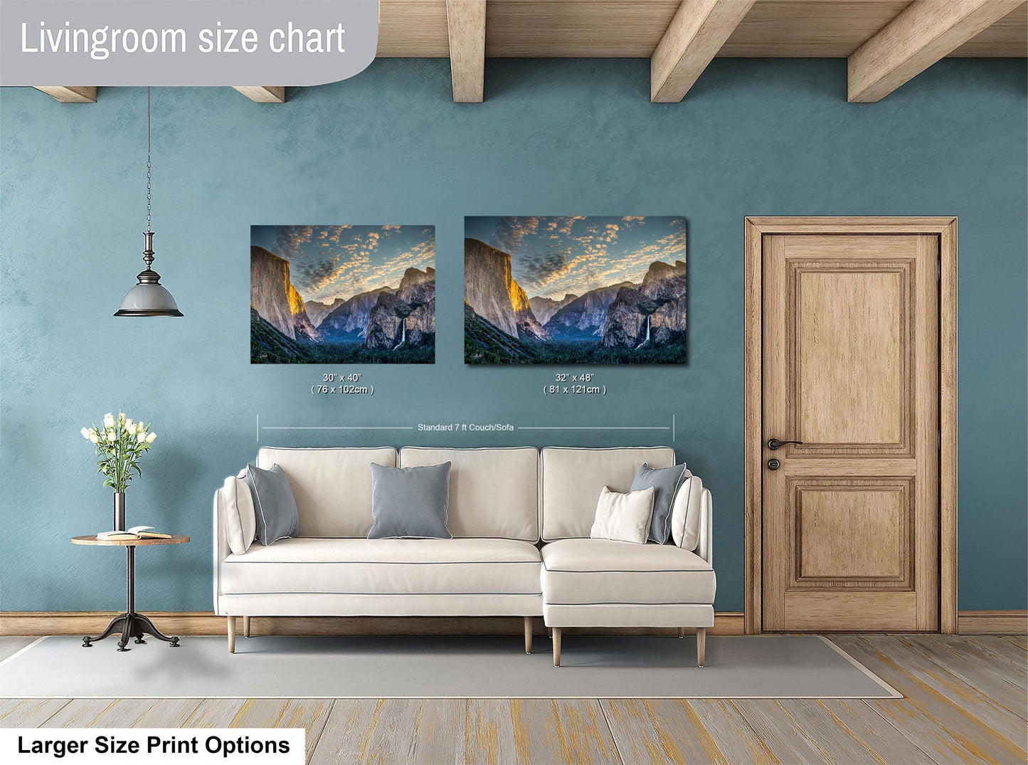 a living room with a white sofa and a wooden door. Above the sofa, there are two framed landscape paintings depicting mountains. The paintings are of similar size and style, and the wall behind them is painted in a light blue color.