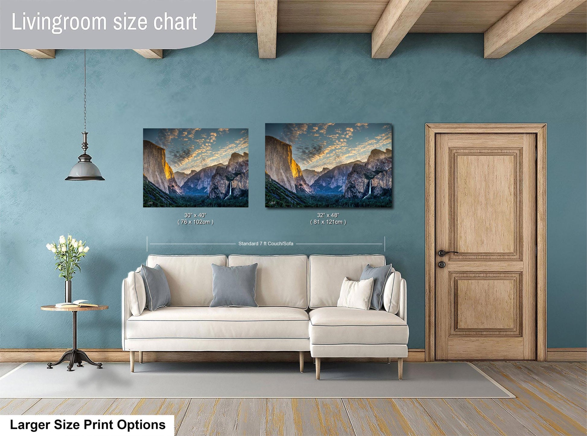 a living room with a white sofa and a wooden door. Above the sofa, there are two framed landscape paintings depicting mountains. The paintings are of similar size and style, and the wall behind them is painted in a light blue color.