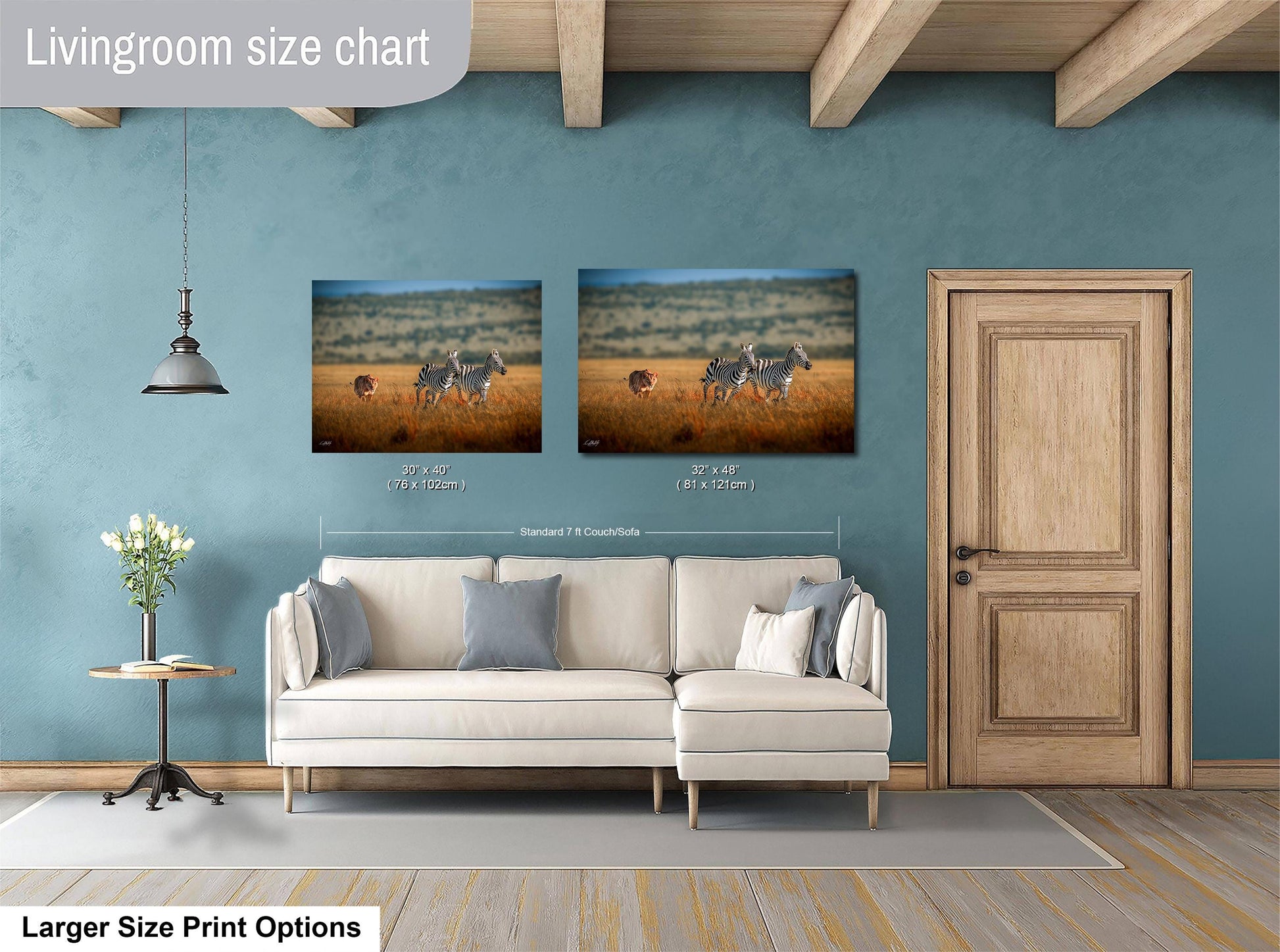 a living room with a white sofa, a wooden door, and two framed prints of zebras in a field. The prints are of different sizes, with one being larger than the other.