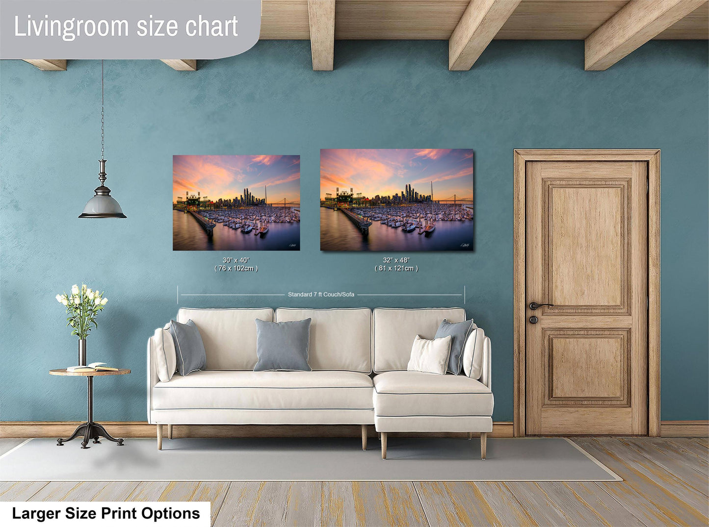 a living room with a white sofa and a wooden door. Above the sofa, there are two framed pictures of a city skyline at sunset, with boats in the water below. The living room has a blue wall and a wooden ceiling.