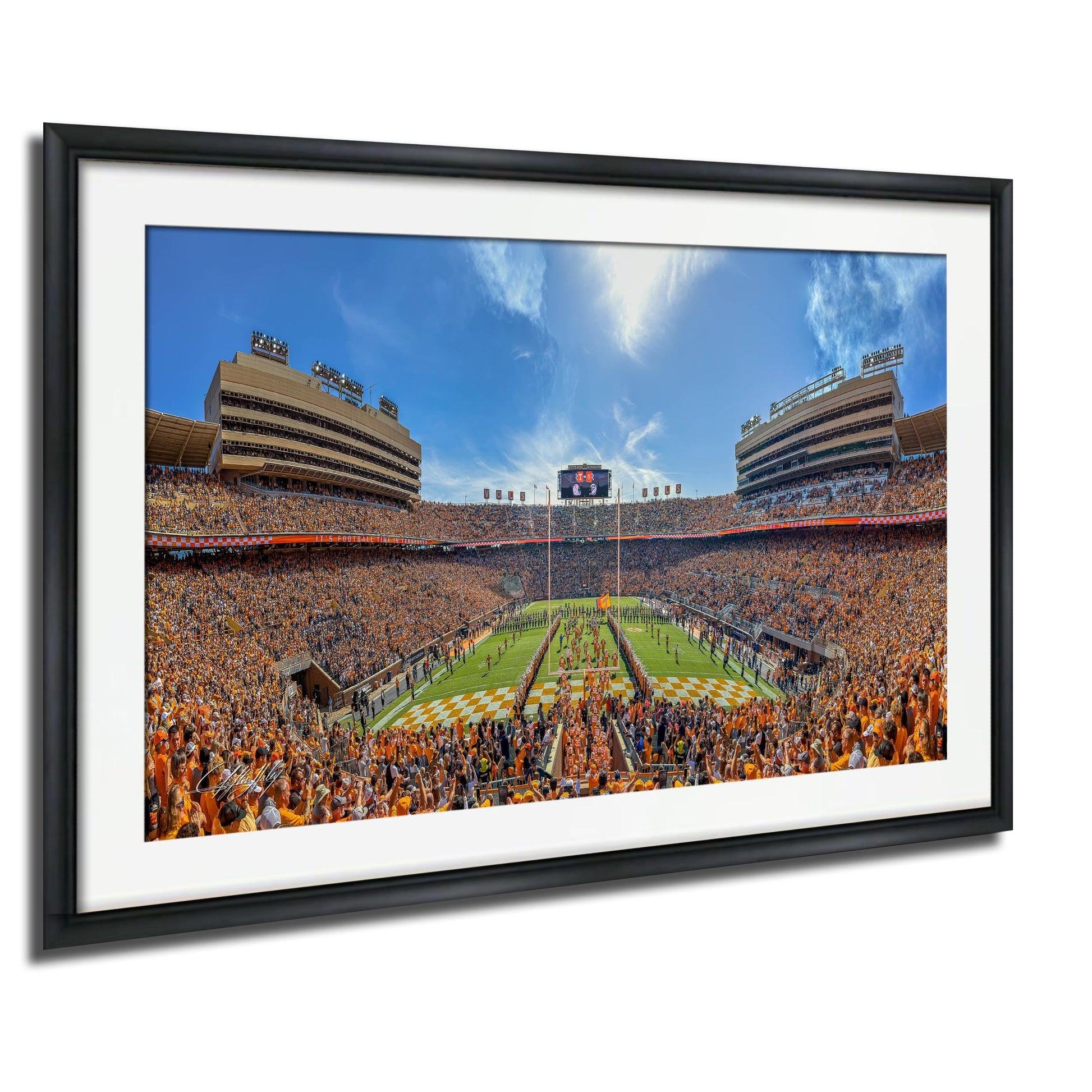 A framed photograph of a crowded football stadium with a large field, multiple levels of seating, and a large scoreboard in the center.