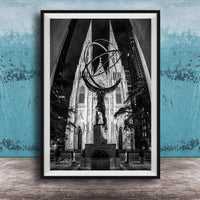 A black and white photograph of a large cathedral with a statue of a man on a pedestal in the foreground, set against a blue wall.