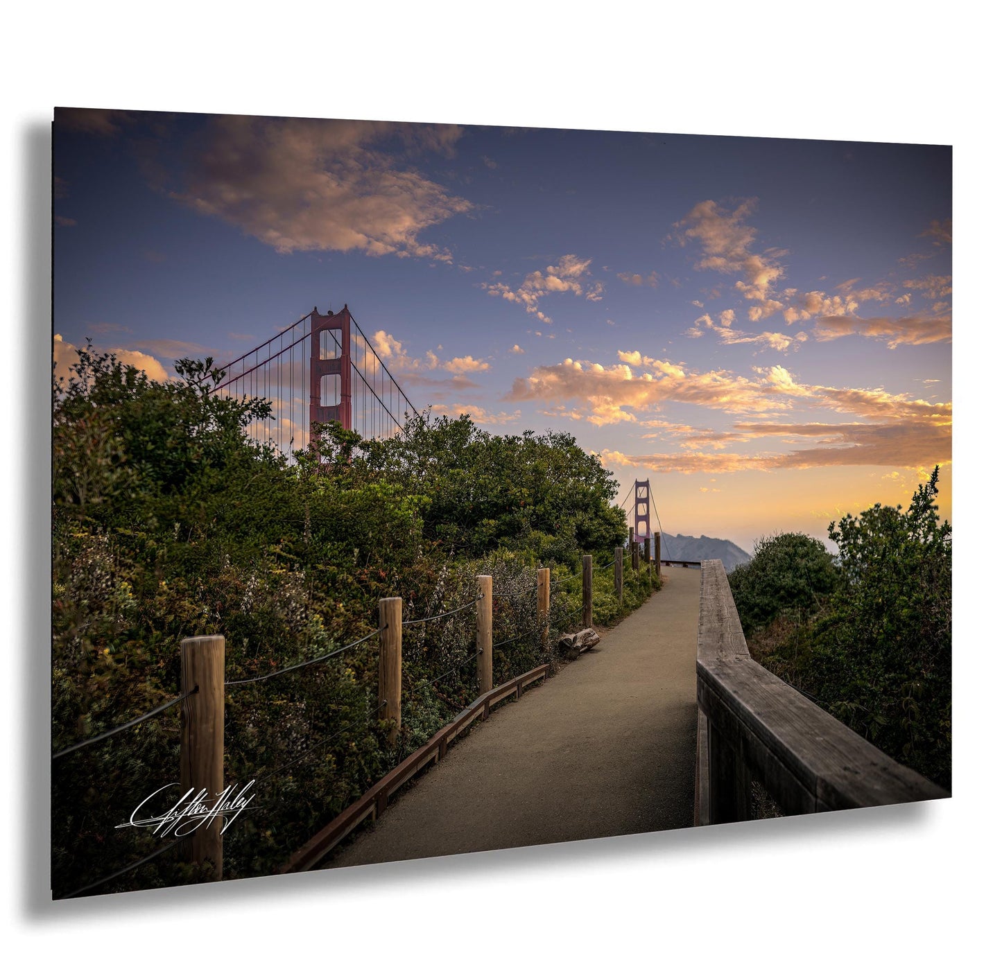 a scenic view of the Golden Gate Bridge at sunset, with a wooden walkway leading towards the iconic structure.