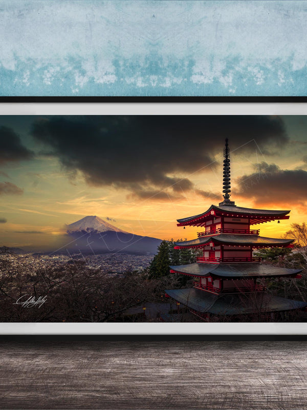 A framed photograph of the Mount Fuji, a famous landmark in Japan, with a red pagoda-style building in the foreground and a dramatic sky in the background.