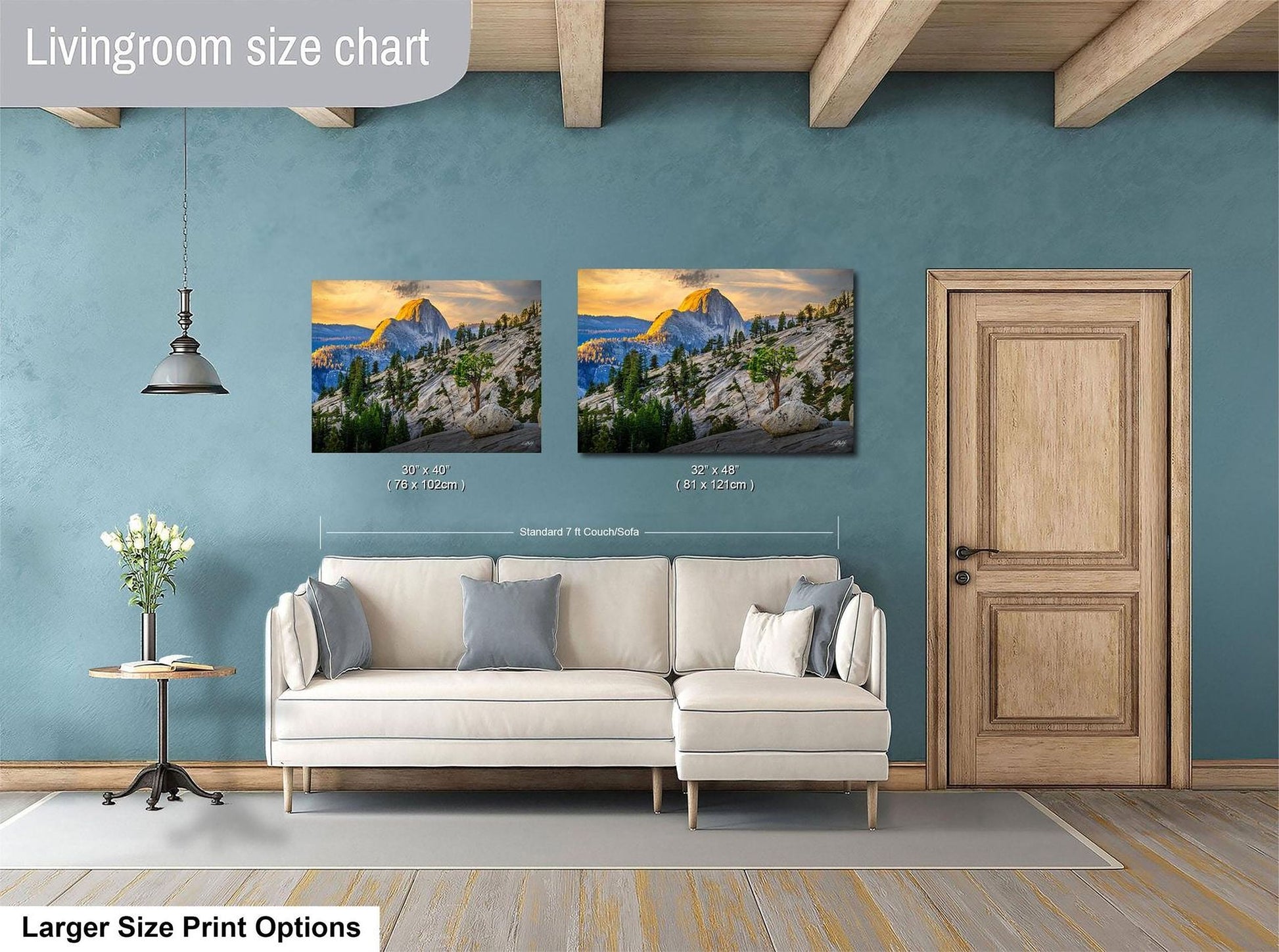 a living room with a white sofa and a wooden door. Above the sofa, there are two framed landscape paintings depicting mountains and forests. The paintings are of similar size, and the wall behind them is painted in a light blue color.