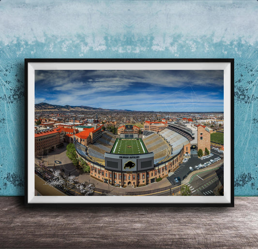 The image is a framed photograph of a football stadium, likely a college or university stadium, with a cityscape in the background.