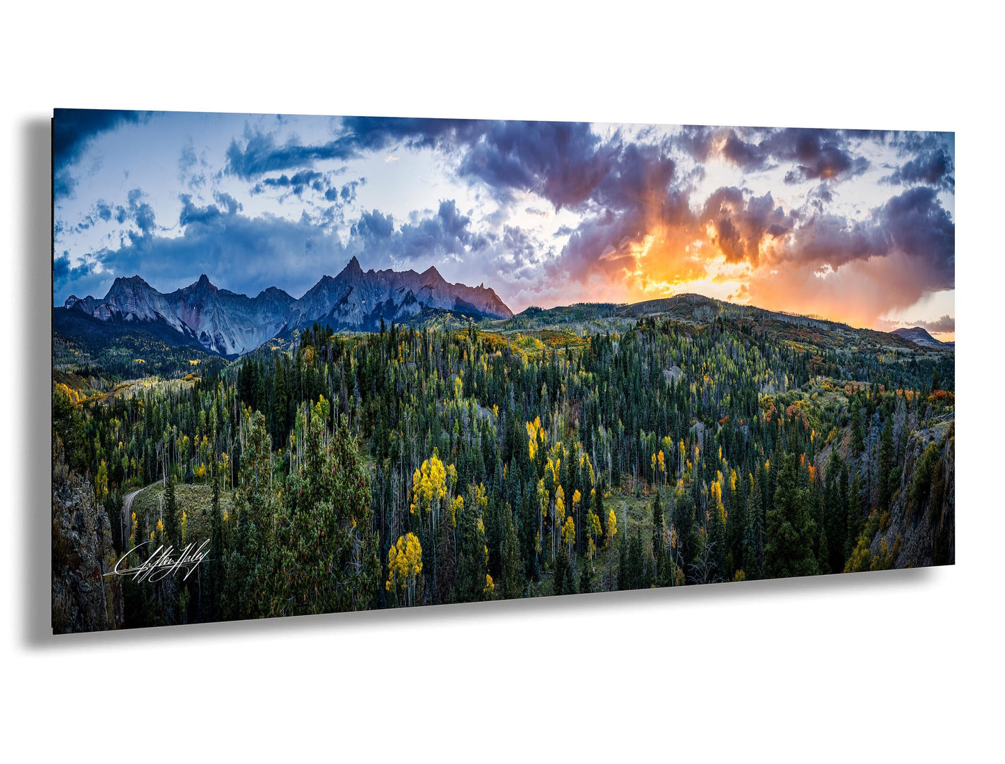 a breathtaking mountainous landscape with a vibrant sunset sky, lush forests, and snow-capped peaks in the distance.