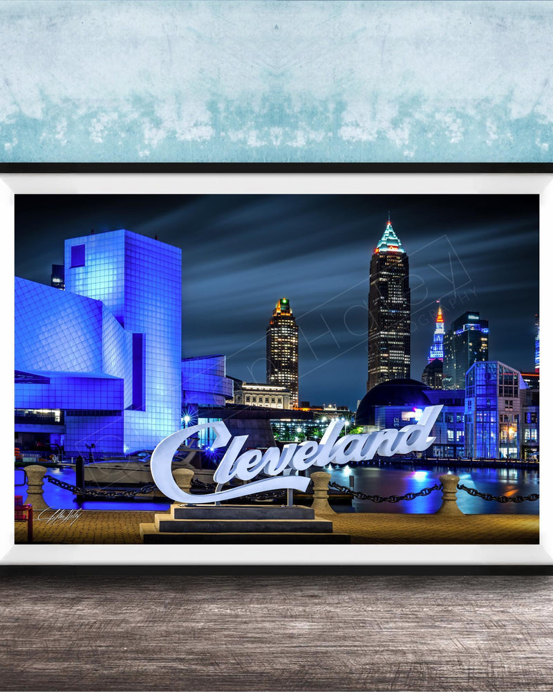 A framed photograph of the Cleveland skyline at night, with the city's iconic landmarks illuminated against a dark sky.