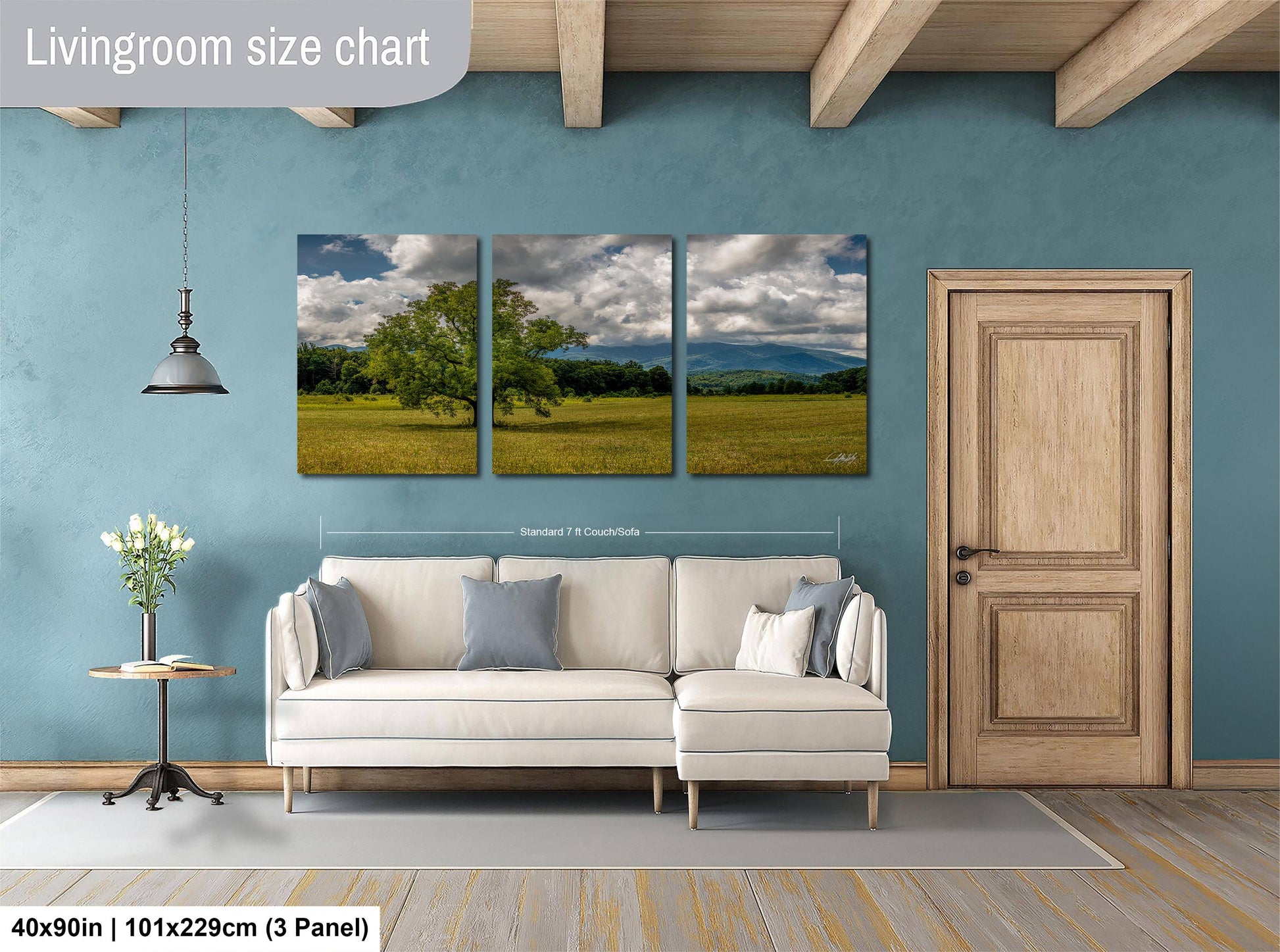 The image is a living room with a white sofa and a wooden door. Above the sofa, there is a triptych of landscape paintings depicting a field with trees and mountains. The wall behind the sofa has a blue color, and there is a lamp hanging from the ceiling. The image is described as a living room size chart, and it is a collage of three images.