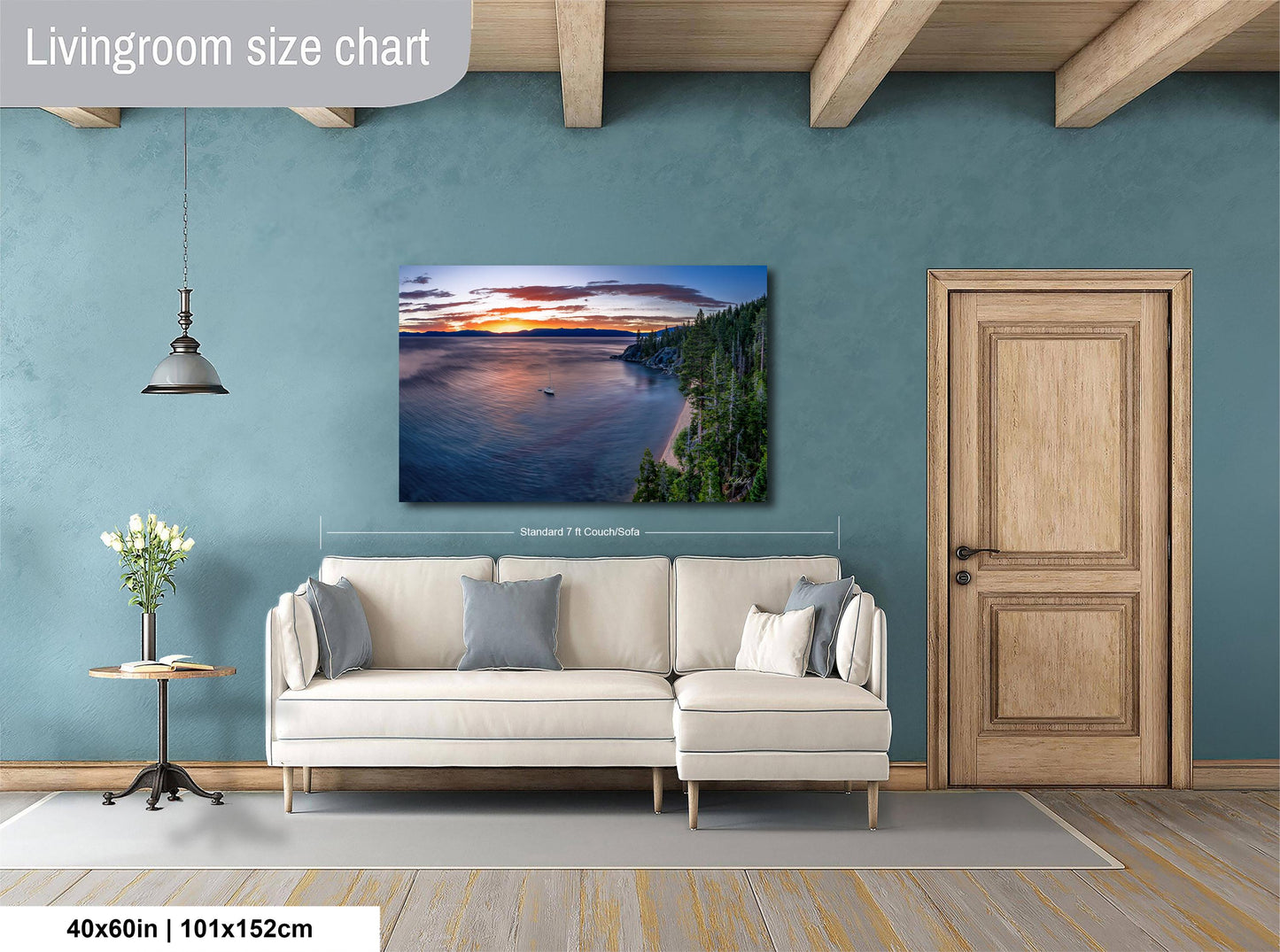 a living room with a large wall painting of a serene landscape featuring a lake, mountains, and a sunset. The painting is framed and hangs above a white sofa with gray throw pillows. The room has a wooden door and a small table with a vase of flowers. The wall is painted in a light blue color, and the floor is covered with a gray rug.