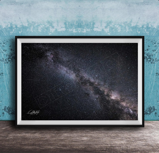 The image is a framed photograph of the night sky, depicting a vast, starry galaxy.