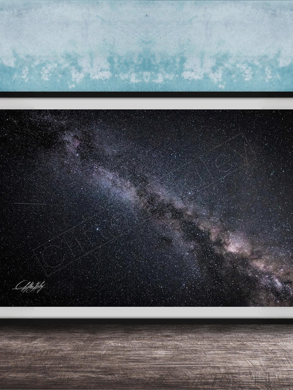 The image is a framed photograph of the night sky, depicting a vast, starry galaxy.