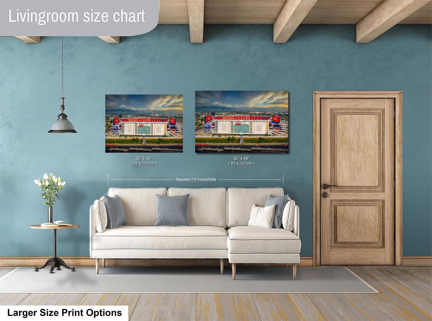 a living room with a white sofa, a wooden door, and two framed pictures of a stadium or sports venue hanging on the wall.