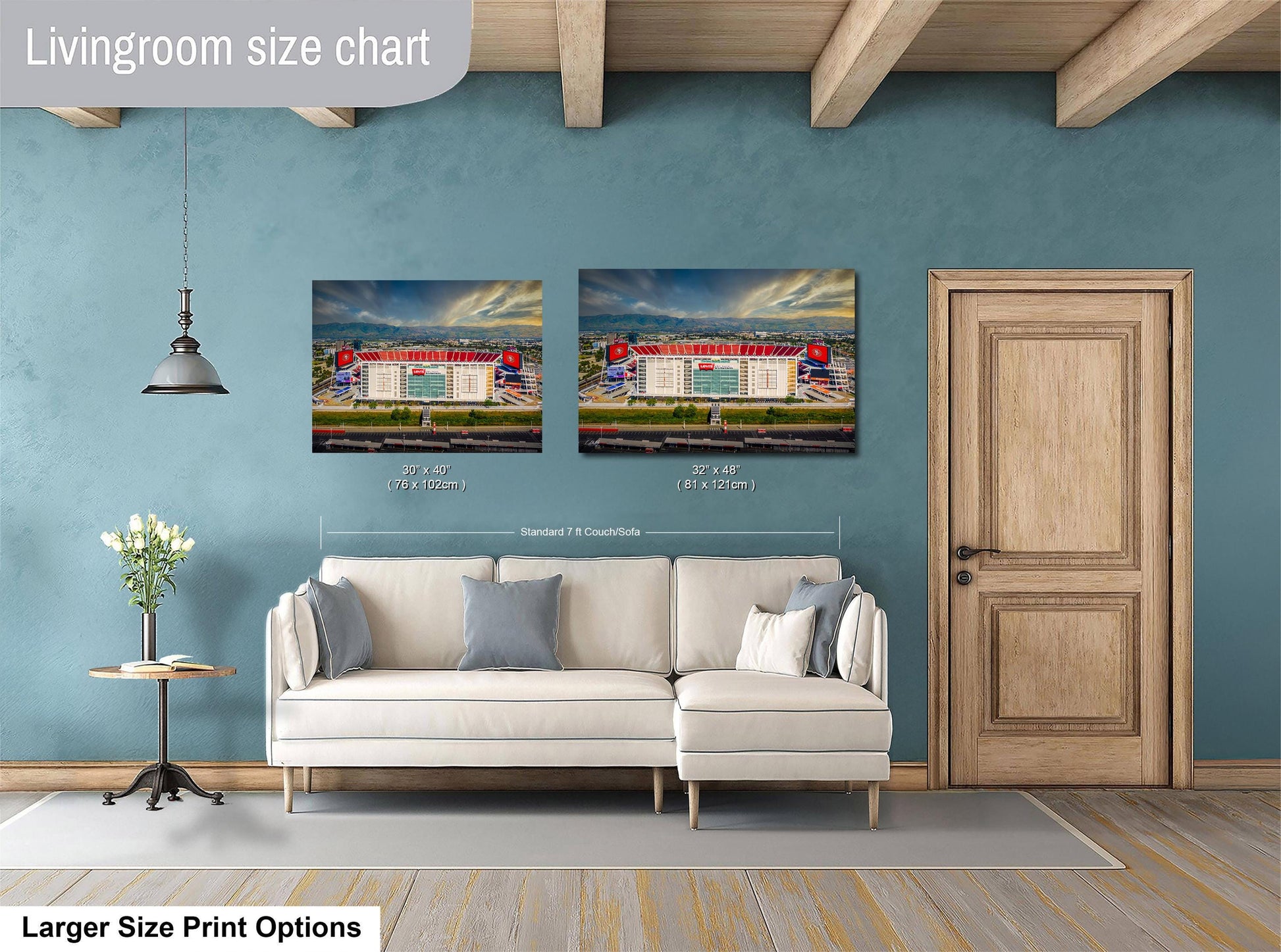 a living room with a white sofa, a wooden door, and two framed pictures of a stadium or sports venue hanging on the wall.