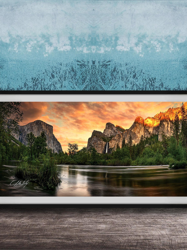 A framed photograph of a scenic mountain landscape at sunset, with a river flowing through the foreground and a waterfall cascading down the mountainside.