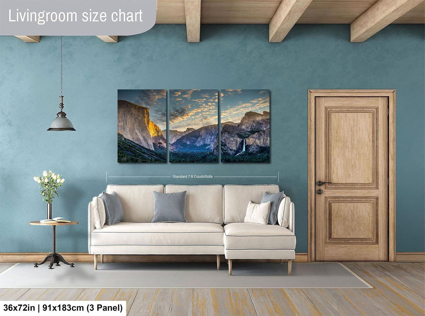 The image is a living room with a large, three-panel landscape painting hanging on the wall. The painting depicts a scenic mountain range with a sunset in the background. The room has a white sofa and a wooden door, creating a cozy and inviting atmosphere.