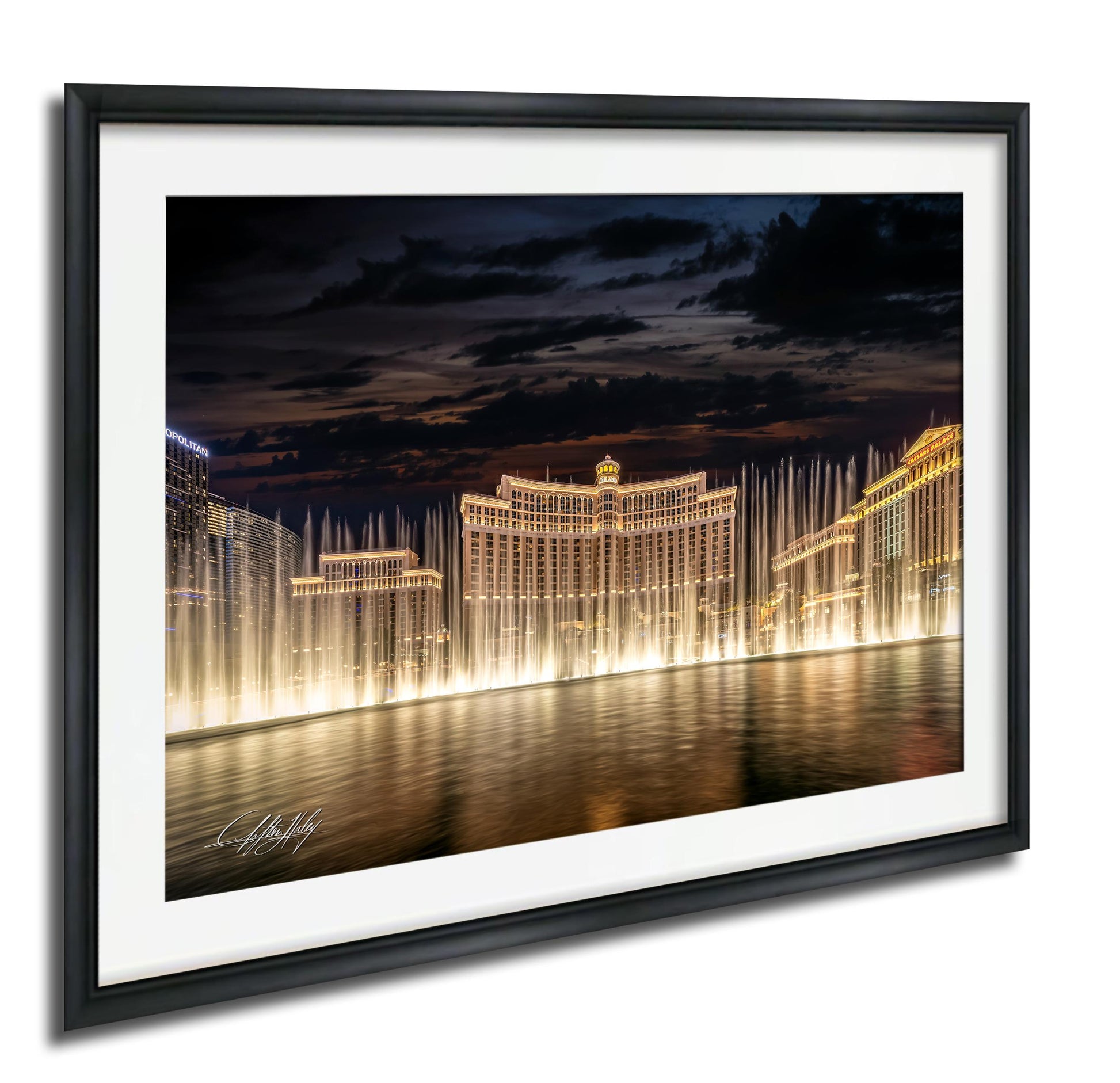 A framed photograph depicting the Bellagio Fountains in Las Vegas at night, with the fountains illuminated and creating a stunning reflection on the water surface.