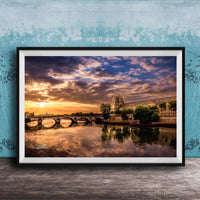 a picturesque scene of a river with a bridge, set against a stunning sunset sky with clouds.