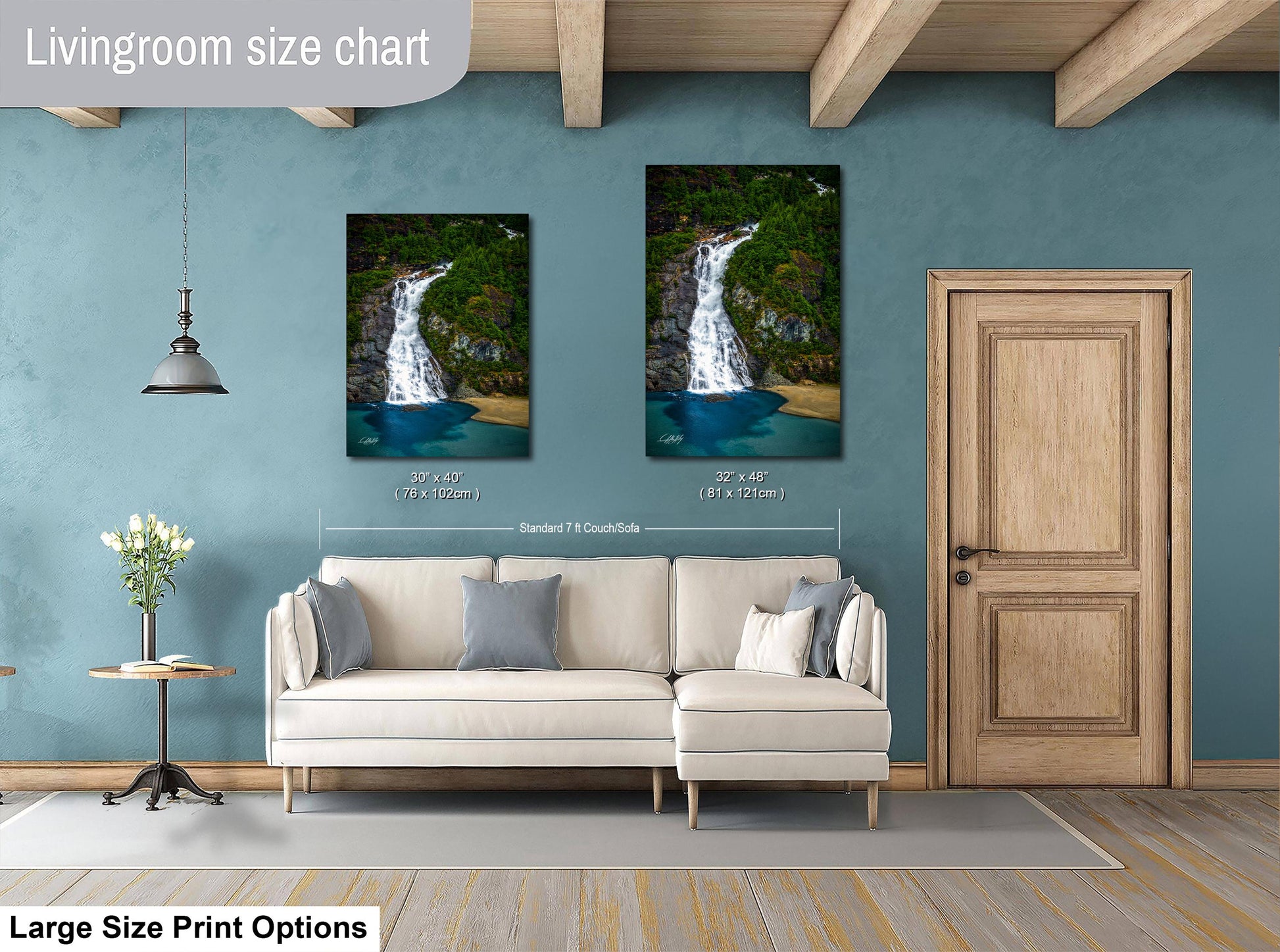 a living room with a white sofa and a wooden door. Above the sofa, there are two framed pictures of a waterfall, one larger than the other. The living room has a blue wall and a wooden ceiling.