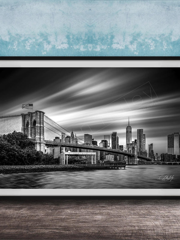 A black and white photograph of the Brooklyn Bridge in New York City, with the city skyline in the background.