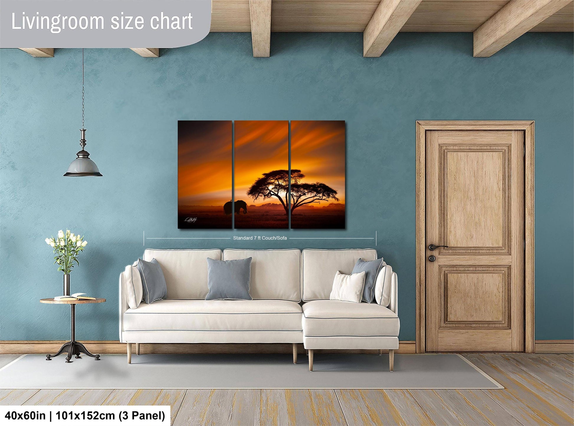 The image is a living room with a large white sofa, a wooden door, and a painting of a sunset on the wall.