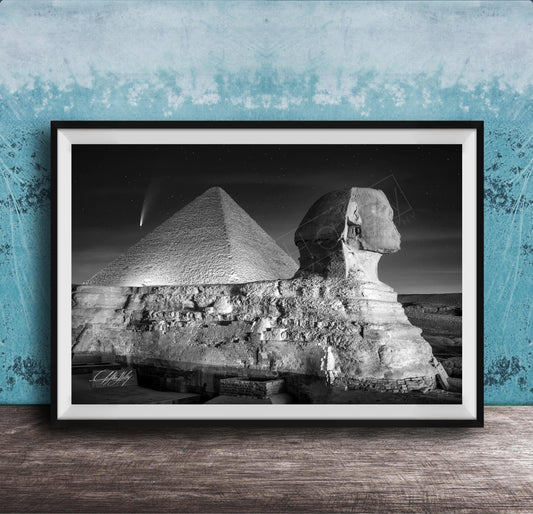 A black and white photograph of the Great Sphinx and the Pyramid of Giza against a night sky, with a small shooting star visible in the sky.