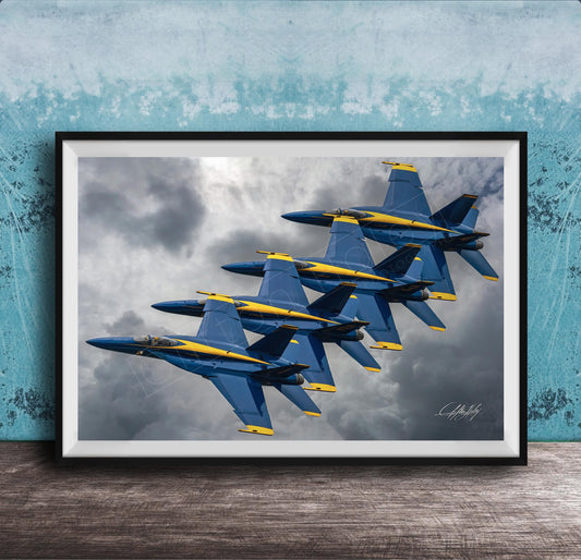 A framed photograph of four blue and yellow fighter jets flying in formation against a cloudy sky.