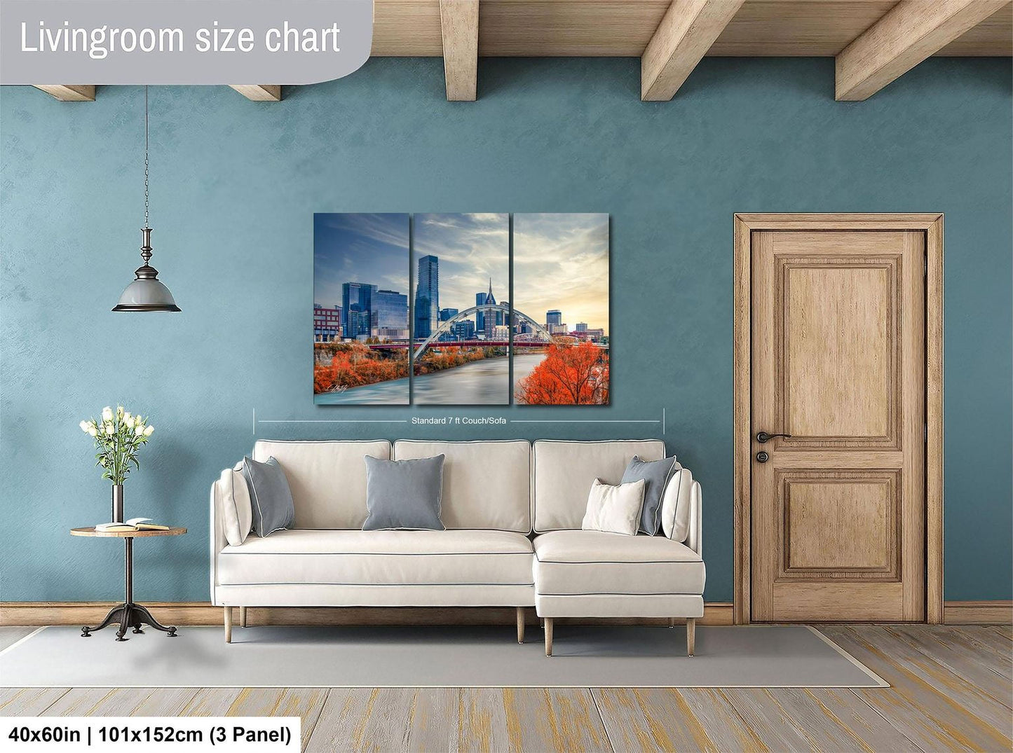 The image is a living room with a large white sofa, a wooden door, and a painting of a city skyline above it.