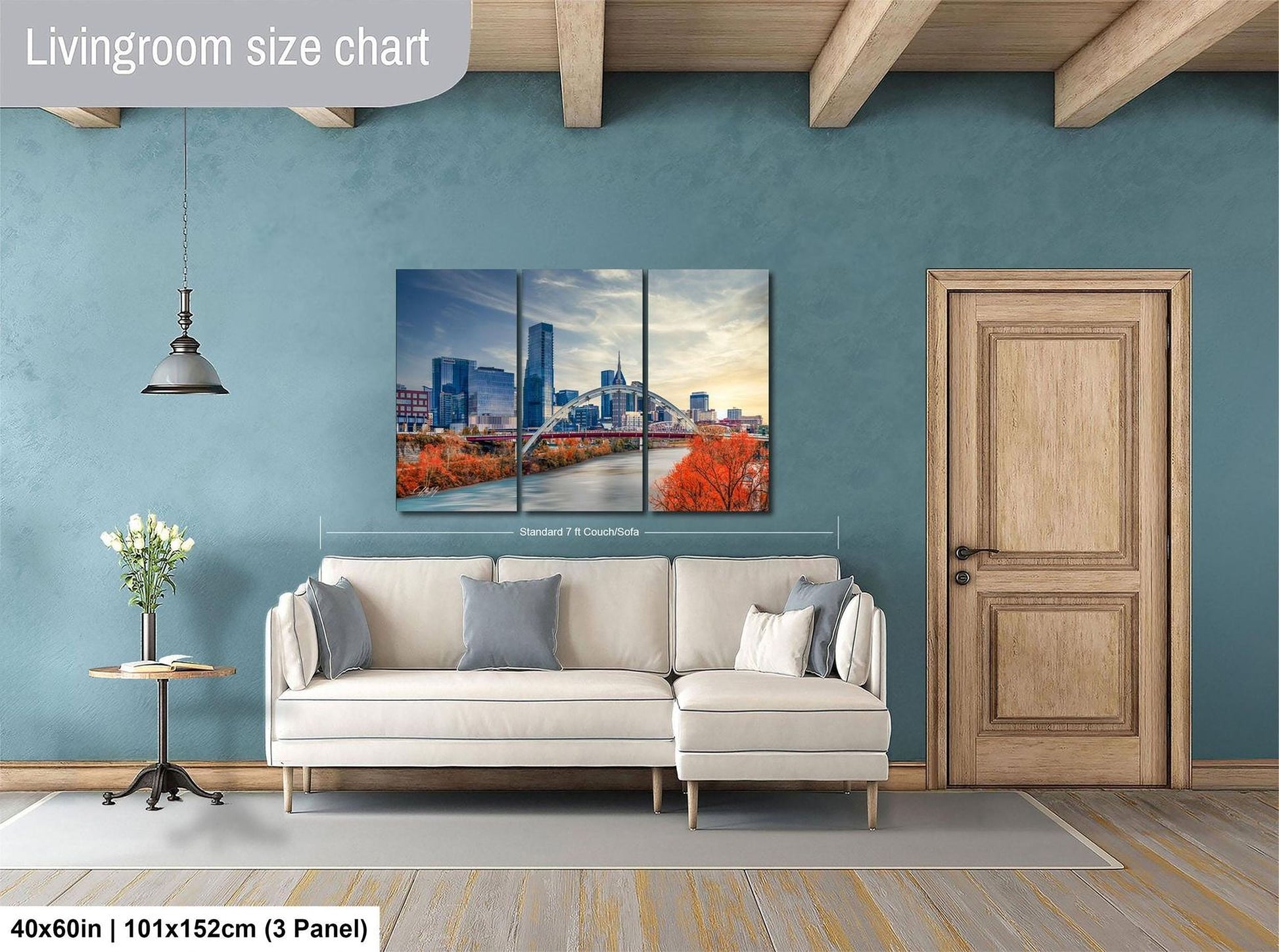 The image is a living room with a large white sofa, a wooden door, and a painting of a city skyline above it.