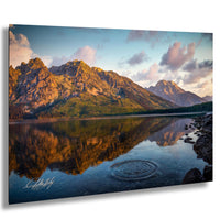 a serene mountain lake with a large ripple effect in the foreground, surrounded by majestic mountains and a beautiful sunset sky.