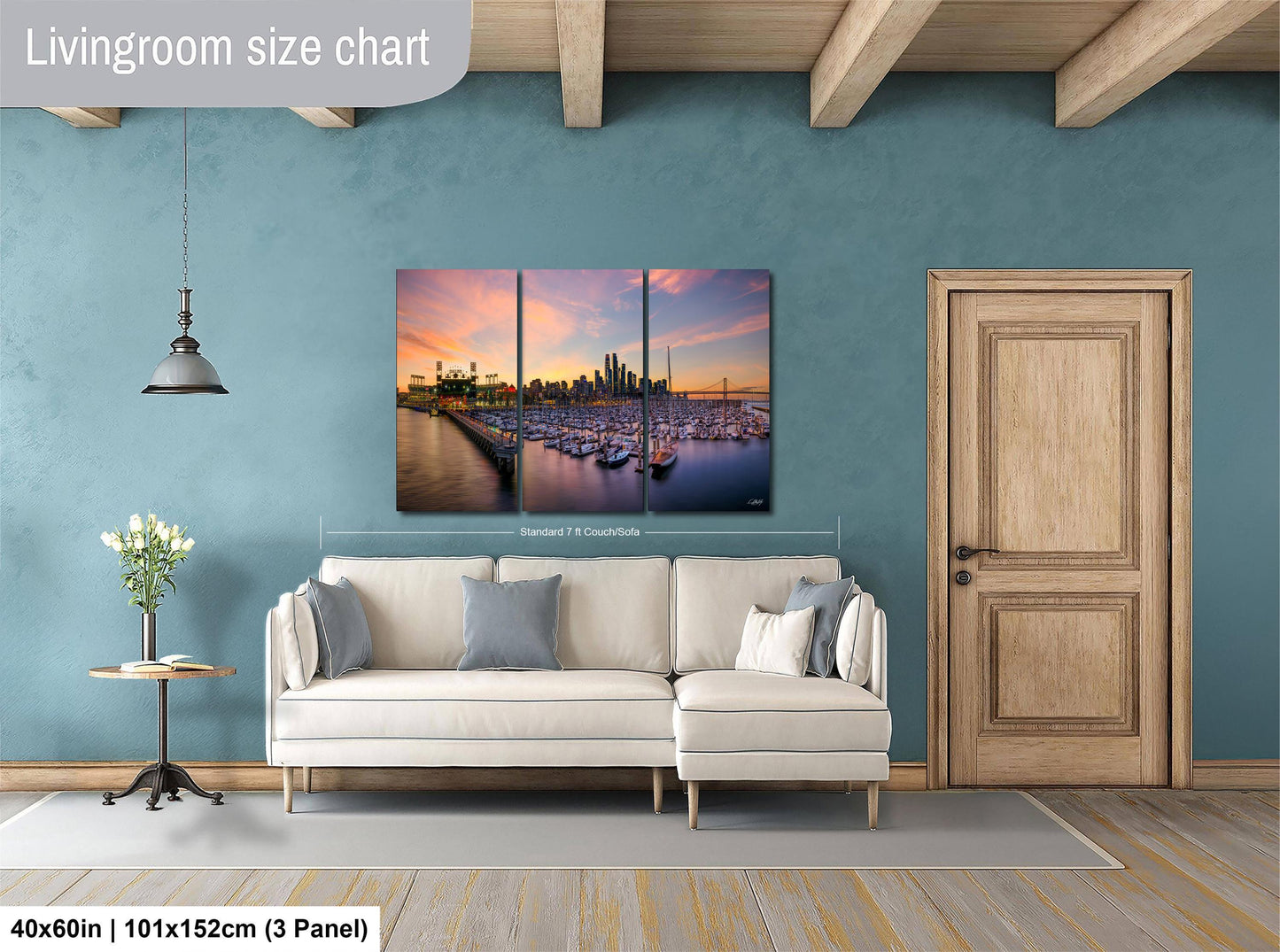 The image is a living room with a large, colorful painting of a city skyline hanging on the wall. The painting is divided into three panels, and the living room has a white sofa, a wooden door, and a small table with a vase of flowers.