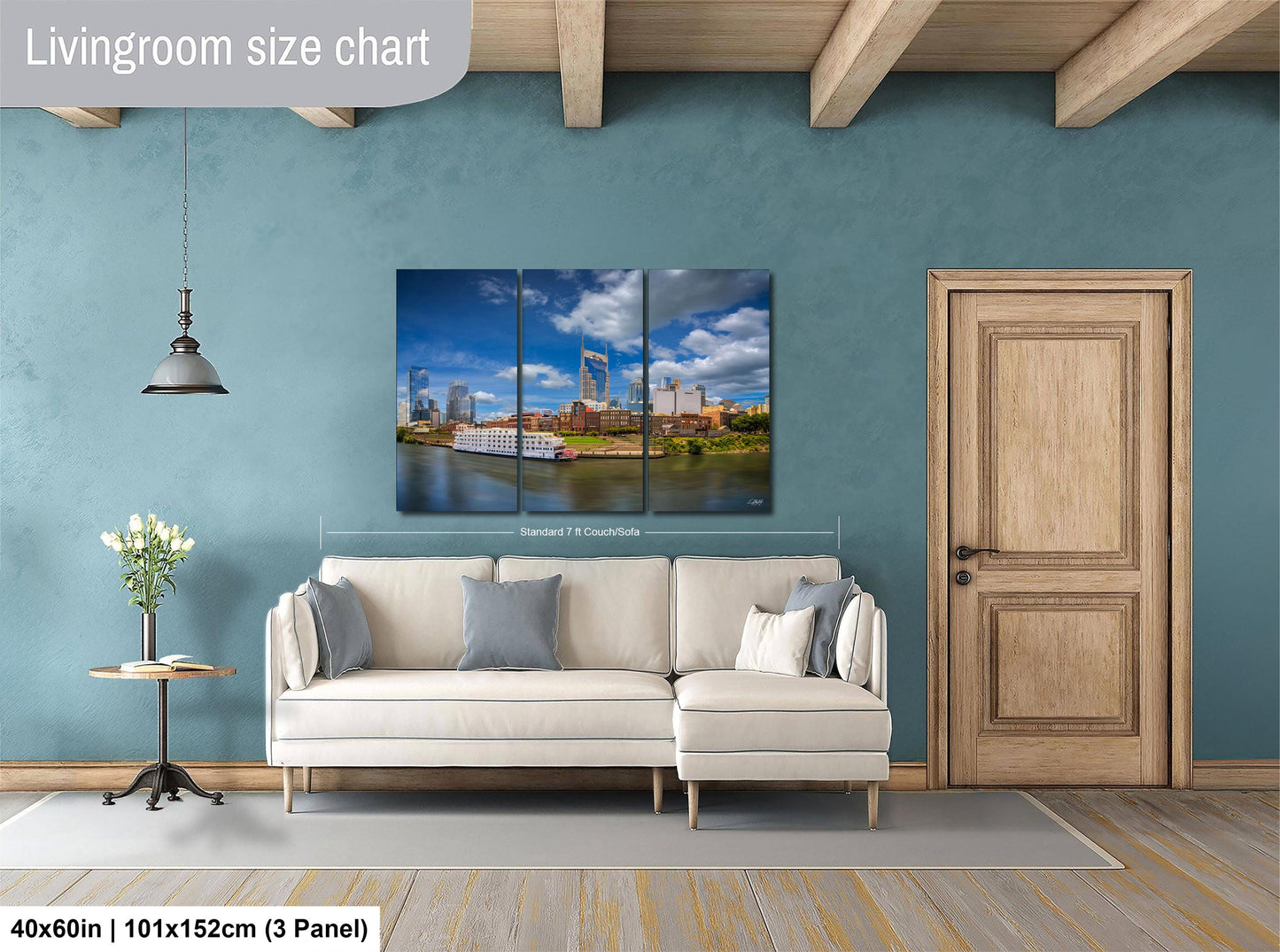 The image is a living room with a large white sofa, a wooden door, and a painting of a city skyline hanging on the wall.